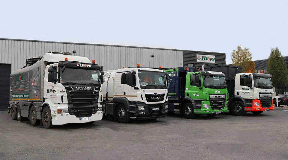 Une flotte de camions blancs stationnés en rangée sur un terminal logistique au coucher du soleil