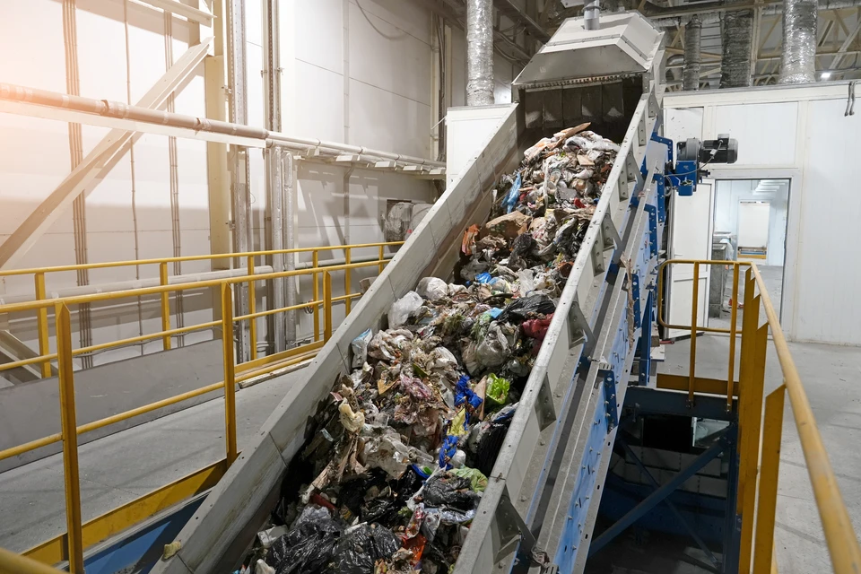 Scène extérieure de chargement logistique : opérateur en combinaison grise conduisant un chariot élévateur orange pour décharger des palettes de matériaux depuis un camion semi-remorque à bâche jaune
